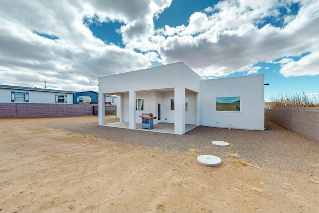 rear view of property with stucco siding, a fenced backyard, and a patio area