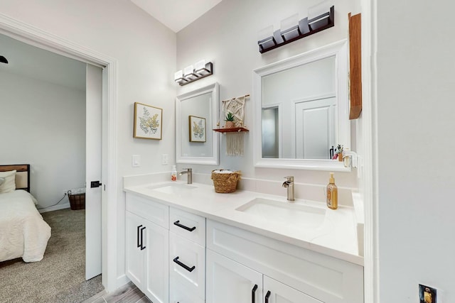 full bathroom featuring double vanity, connected bathroom, baseboards, and a sink