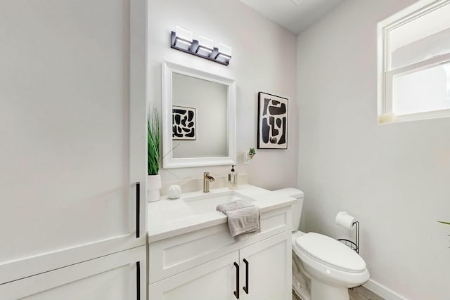 bathroom with toilet, vanity, and baseboards