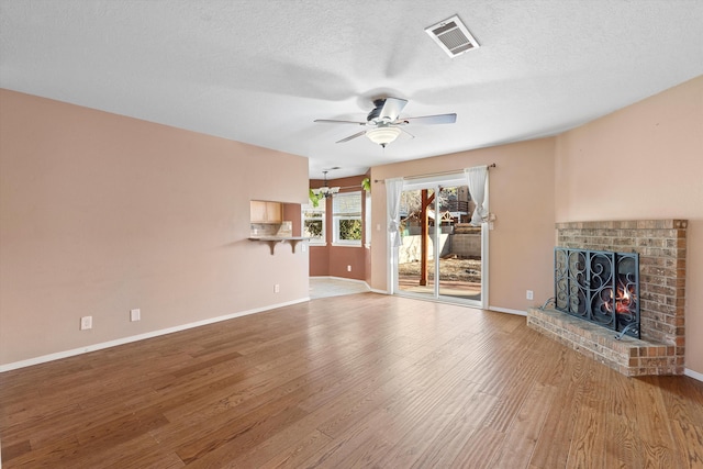 unfurnished living room featuring ceiling fan, visible vents, wood finished floors, and a fireplace