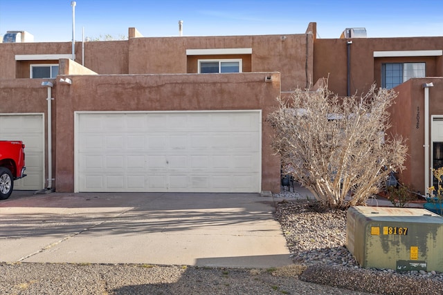 southwest-style home with a garage, driveway, and stucco siding