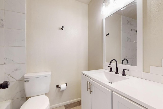 bathroom featuring vanity, toilet, a shower, and baseboards