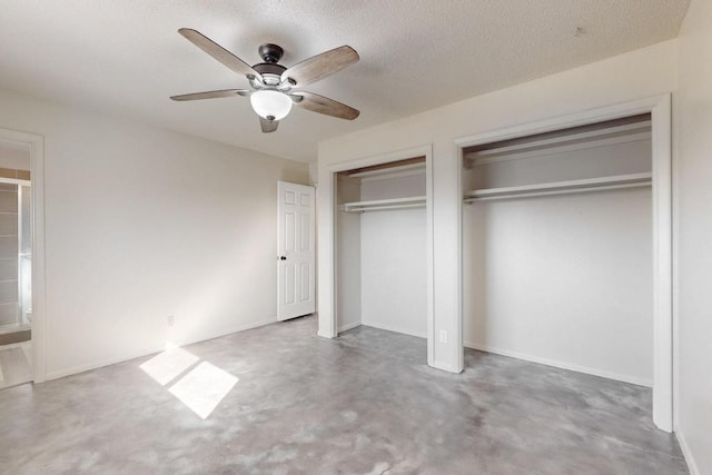 unfurnished bedroom featuring two closets, a textured ceiling, concrete floors, baseboards, and ceiling fan