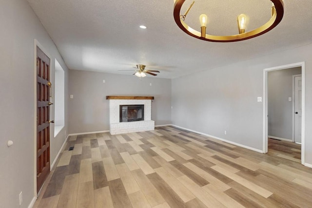 unfurnished living room featuring a textured ceiling, baseboards, light wood finished floors, and ceiling fan