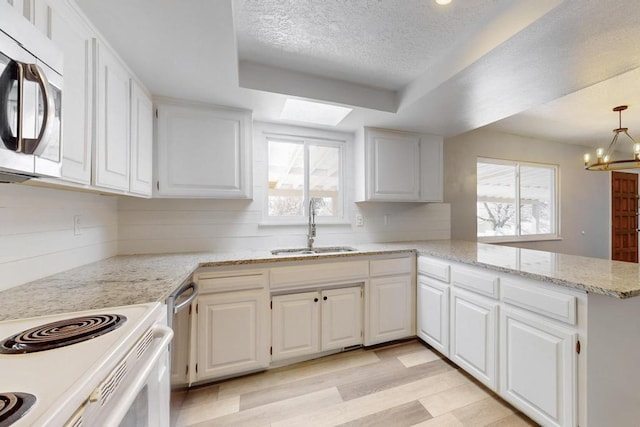 kitchen with white cabinets, appliances with stainless steel finishes, a skylight, and a sink