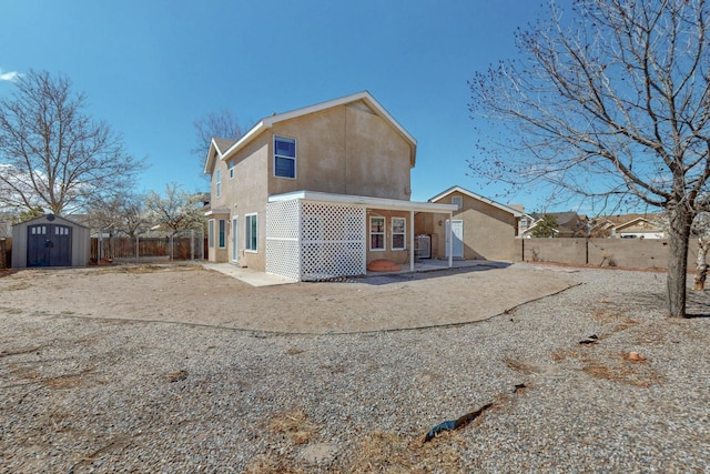 rear view of property with an outbuilding, a fenced backyard, a shed, and stucco siding