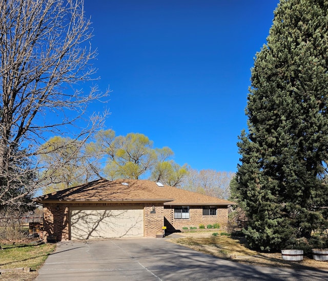 ranch-style house with a garage, brick siding, driveway, and a shingled roof