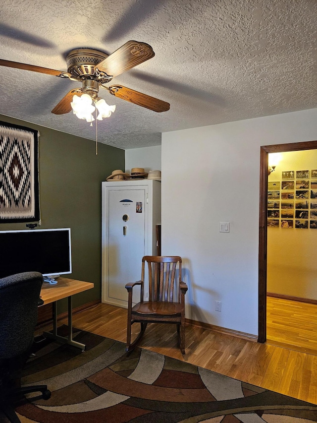 office space featuring baseboards, a textured ceiling, wood finished floors, and a ceiling fan