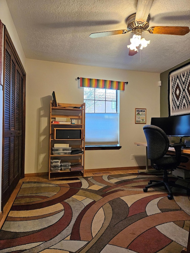 office space with baseboards, a textured ceiling, a ceiling fan, and carpet floors