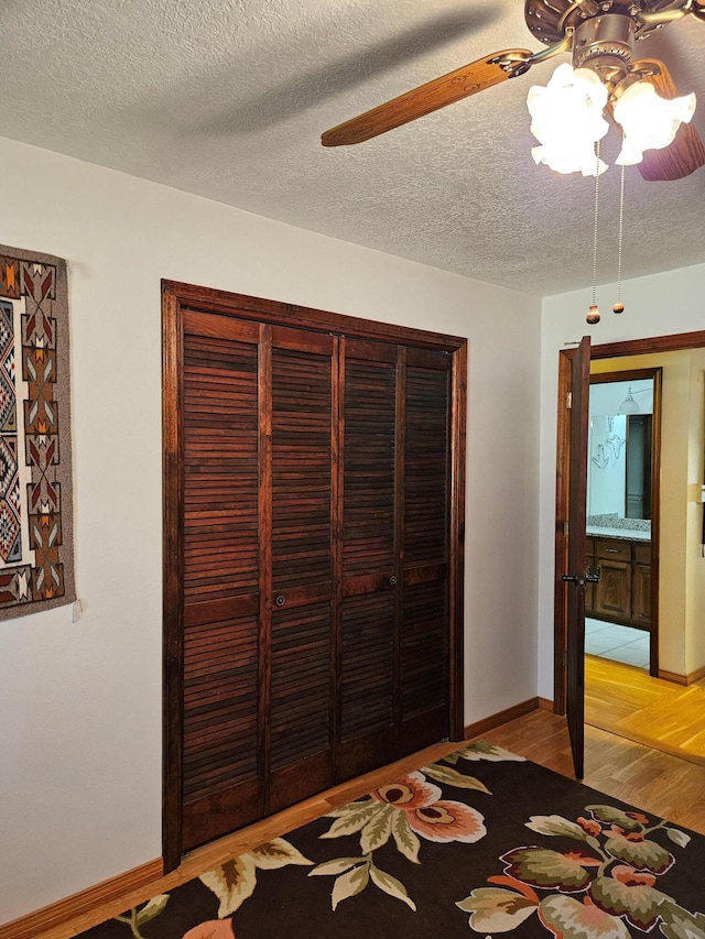 unfurnished bedroom featuring light wood finished floors, a textured ceiling, baseboards, and a closet