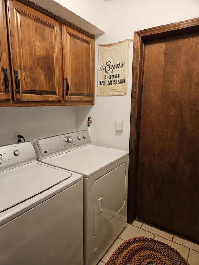 laundry area featuring light tile patterned floors, cabinet space, and separate washer and dryer