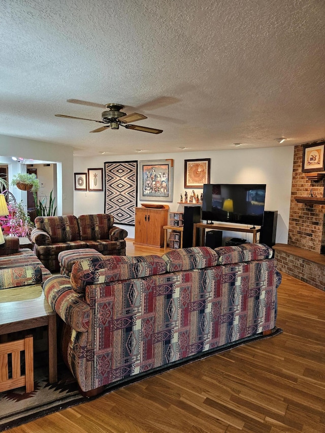 living area featuring a textured ceiling, wood finished floors, and a ceiling fan