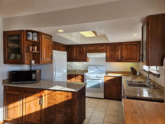 kitchen with under cabinet range hood, white appliances, a textured ceiling, and a sink