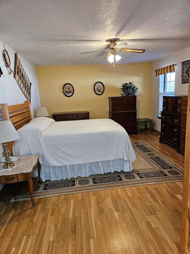 bedroom with a textured ceiling, a ceiling fan, and wood finished floors