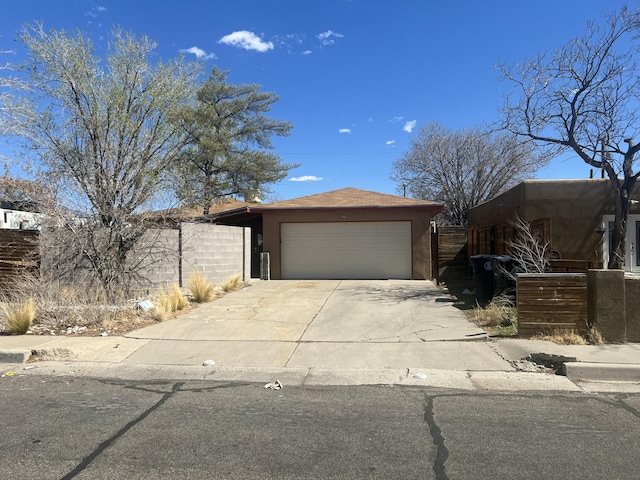 view of front of home featuring concrete driveway, fence, a garage, and stucco siding