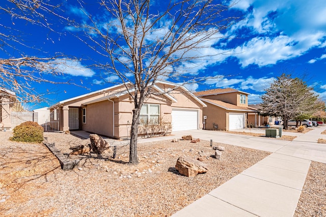 view of front of home featuring concrete driveway, an attached garage, fence, and stucco siding