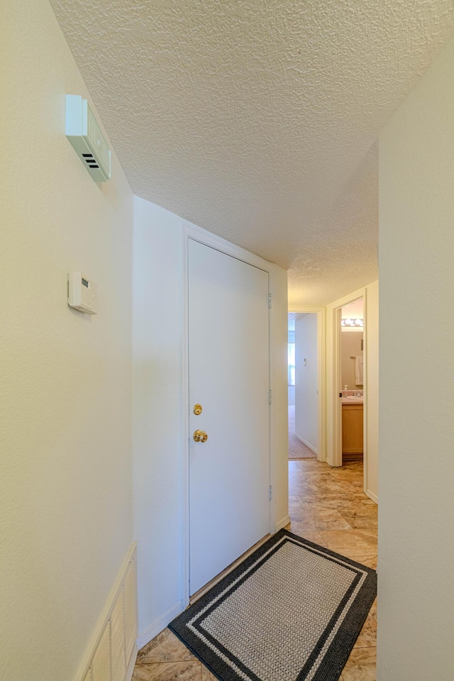 hallway with visible vents and a textured ceiling