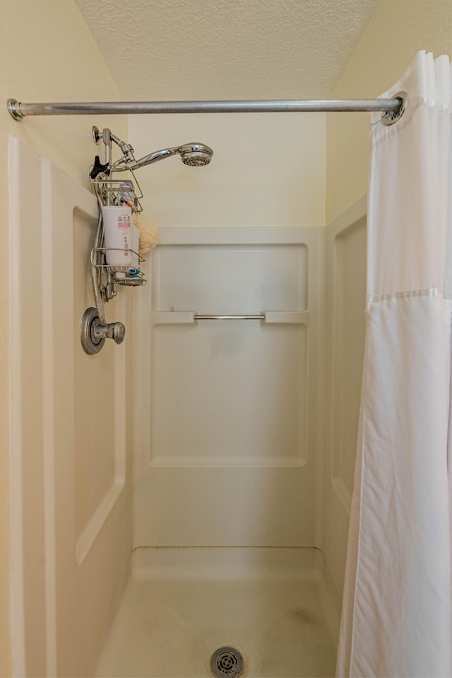 bathroom featuring a textured ceiling and a stall shower