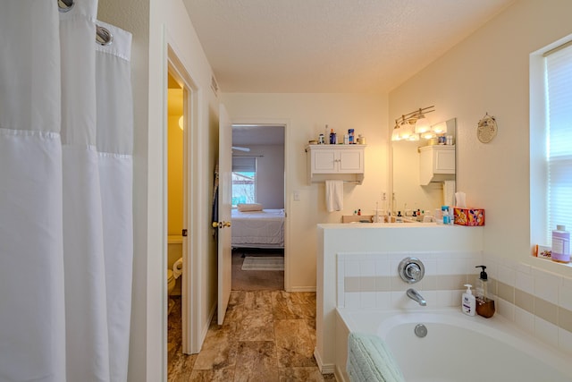 ensuite bathroom featuring a bath, visible vents, a textured ceiling, and ensuite bath