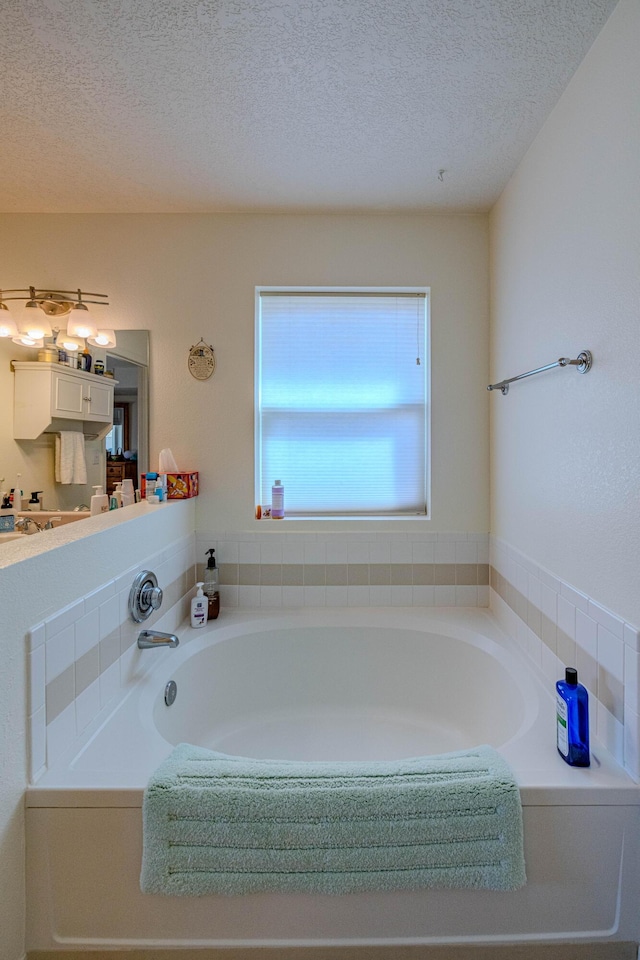 full bath featuring a garden tub and a textured ceiling