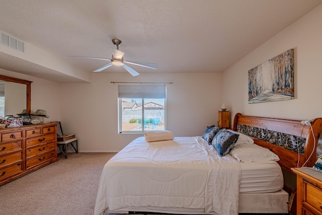 carpeted bedroom featuring baseboards, a ceiling fan, visible vents, and a textured ceiling