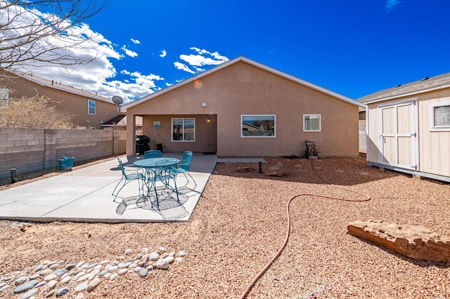 back of house with a patio, fence, stucco siding, an outdoor structure, and a storage shed