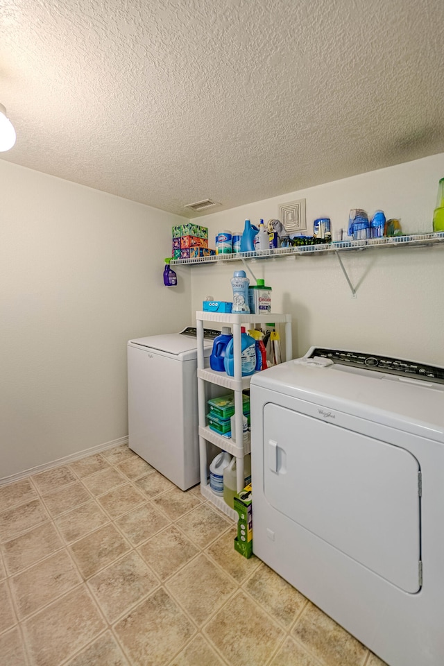 laundry room with a textured ceiling, laundry area, baseboards, and washer and clothes dryer