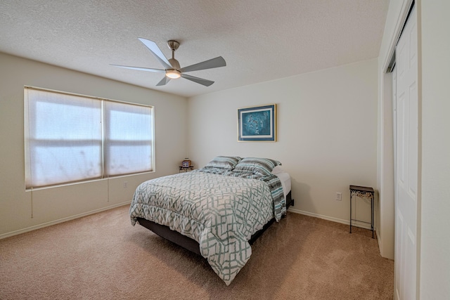 bedroom featuring a ceiling fan, a textured ceiling, a closet, baseboards, and light colored carpet