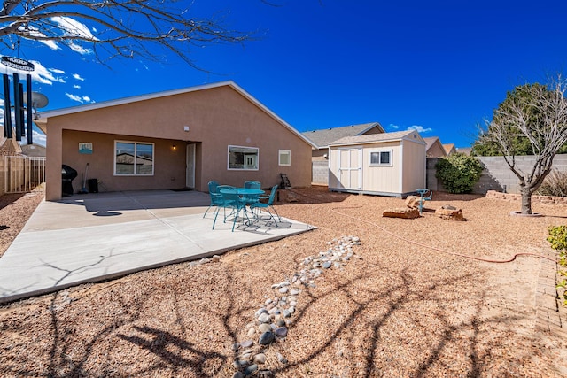 back of house with an outdoor structure, a storage unit, a fenced backyard, and stucco siding