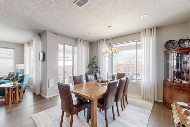 dining space with a wealth of natural light, visible vents, a notable chandelier, and light wood finished floors