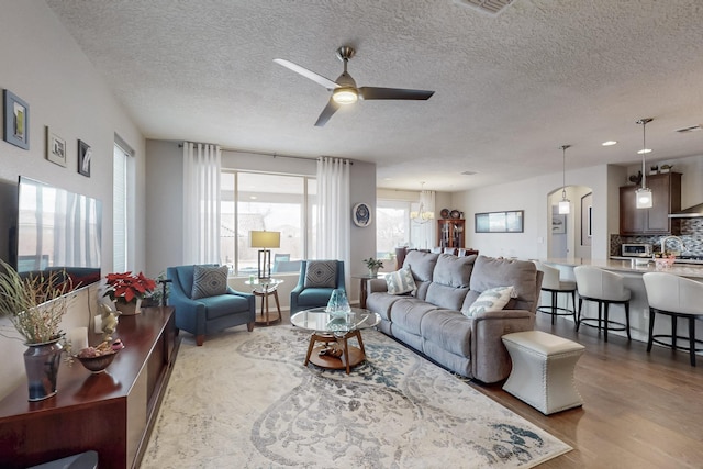 living room featuring a textured ceiling, wood finished floors, and a ceiling fan