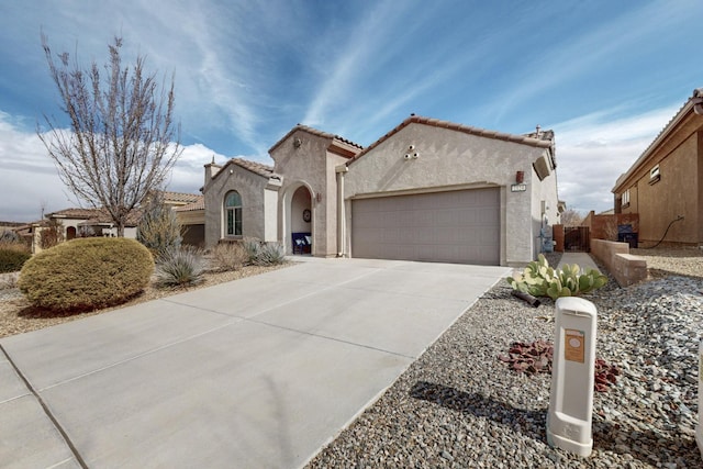 mediterranean / spanish house with a garage, stucco siding, driveway, and a tiled roof