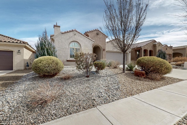 mediterranean / spanish house featuring stucco siding, a tiled roof, and a garage