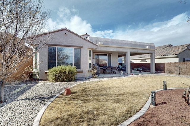 rear view of property with a patio area, a lawn, and stucco siding