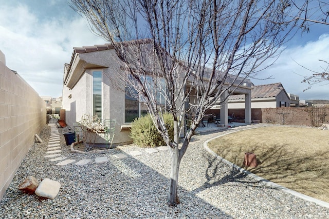 exterior space with a fenced backyard, stucco siding, a tiled roof, and a patio