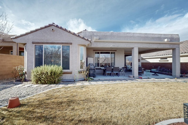 back of property featuring stucco siding, a patio, a lawn, and fence