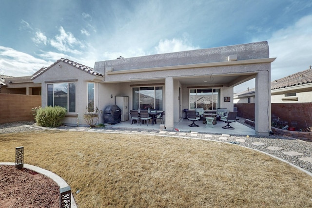 rear view of property with a yard, fence, stucco siding, and a patio area