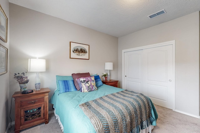 bedroom with visible vents, a textured ceiling, a closet, carpet flooring, and baseboards