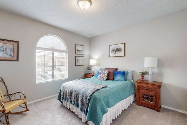 bedroom featuring a textured ceiling, baseboards, and carpet