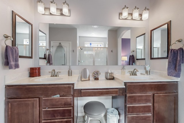 bathroom featuring double vanity, a shower stall, and a sink