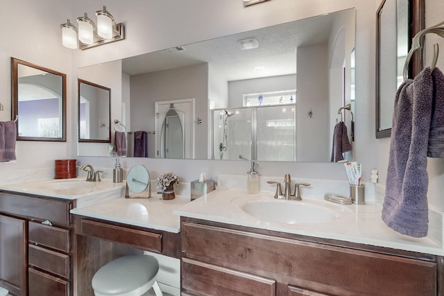 bathroom featuring a shower stall, double vanity, and a sink