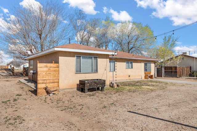 back of house featuring stucco siding and fence