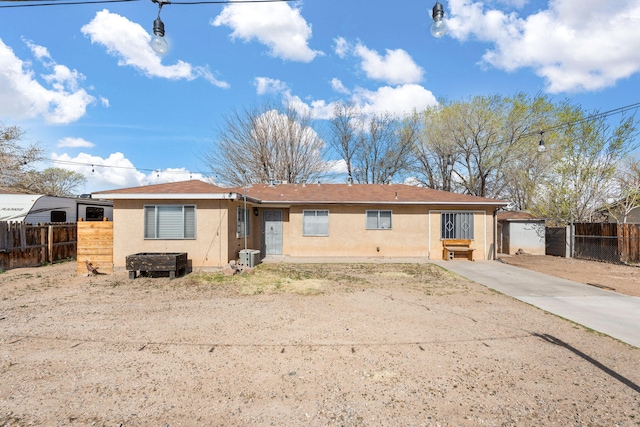 single story home with concrete driveway, fence, central AC, and stucco siding