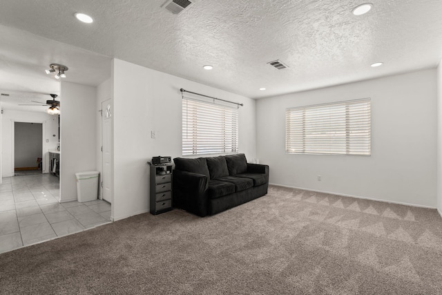 living area with tile patterned flooring, visible vents, carpet floors, and a textured ceiling