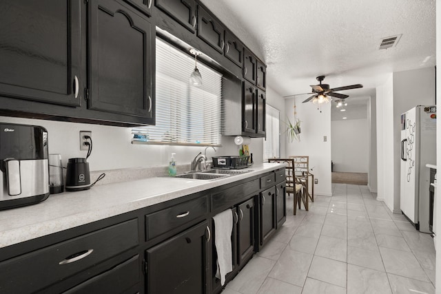 kitchen featuring ceiling fan, visible vents, and dark cabinets