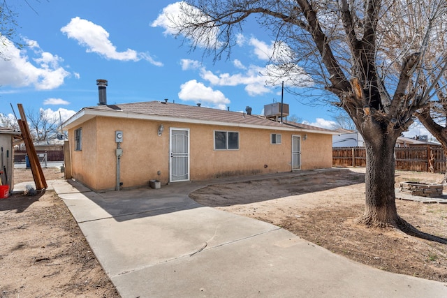 back of house featuring stucco siding, a patio area, roof with shingles, and fence