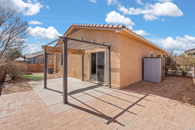 rear view of property with stucco siding, a pergola, a patio, and fence