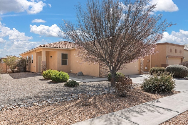 view of side of property with fence, a tile roof, concrete driveway, stucco siding, and an attached garage