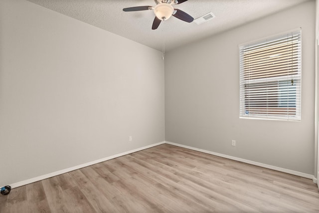 empty room with a textured ceiling, light wood-style flooring, visible vents, and ceiling fan