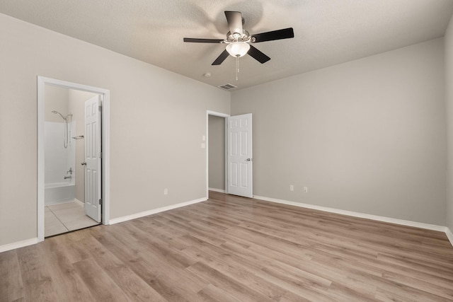 unfurnished bedroom with visible vents, baseboards, light wood-type flooring, ensuite bathroom, and a textured ceiling